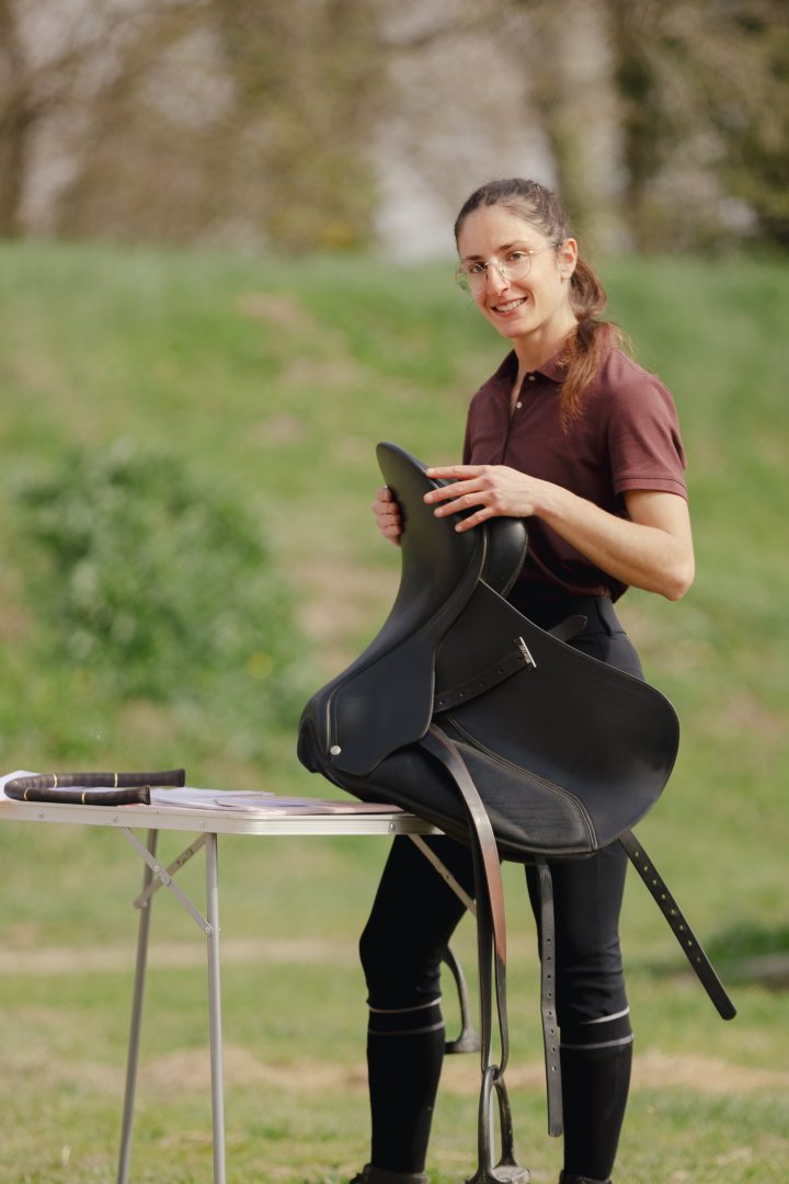 Camille Tao Bordaberry, enseignante d'équitation spécialisée en dressage, locomotion et biomécanique, et saddle fitter certifiée par Ergonomie Équestre, tenant une selle de dressage Wintec.